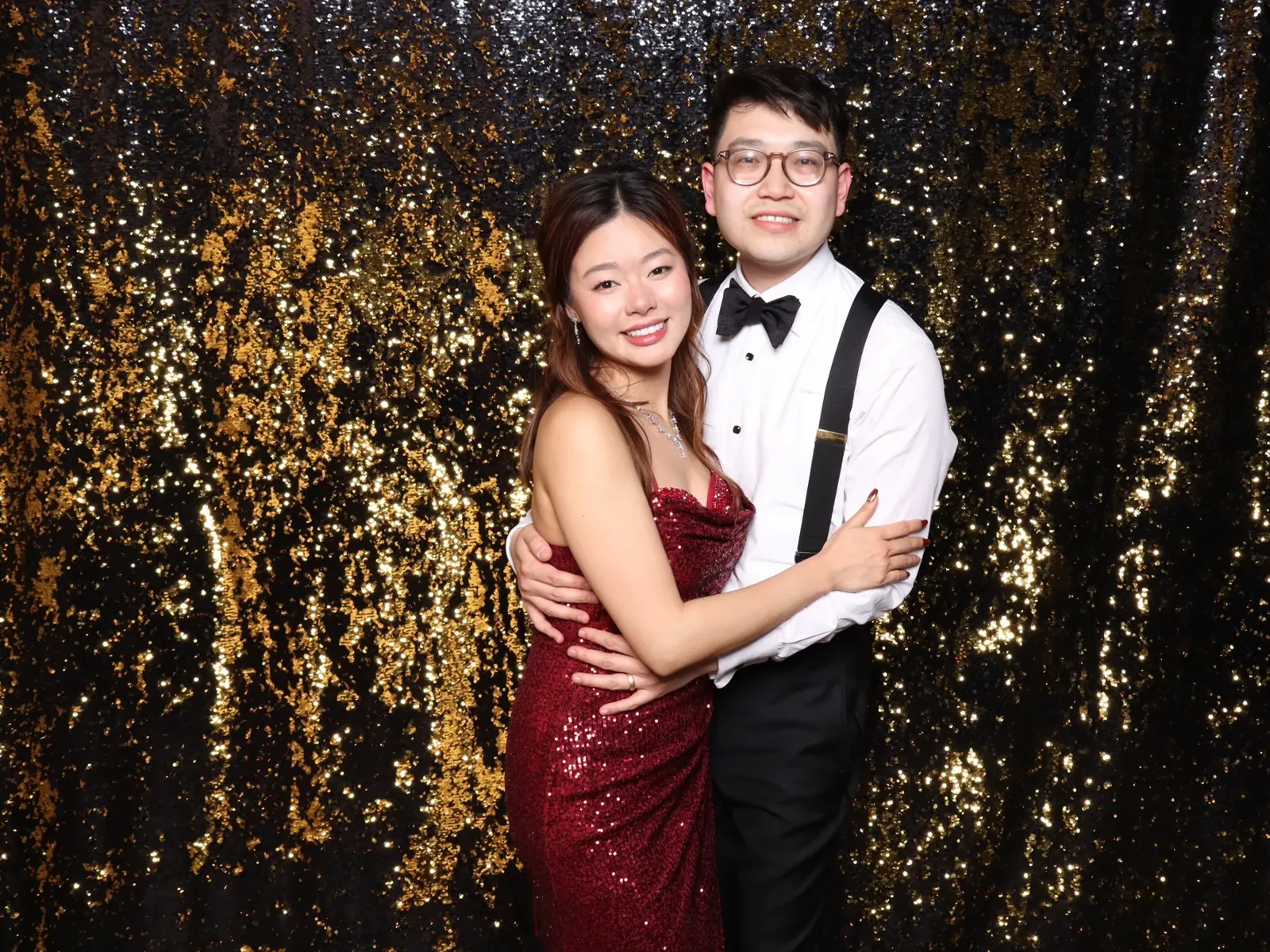 Couple in formal wear against a black and gold sequin photo booth backdrop