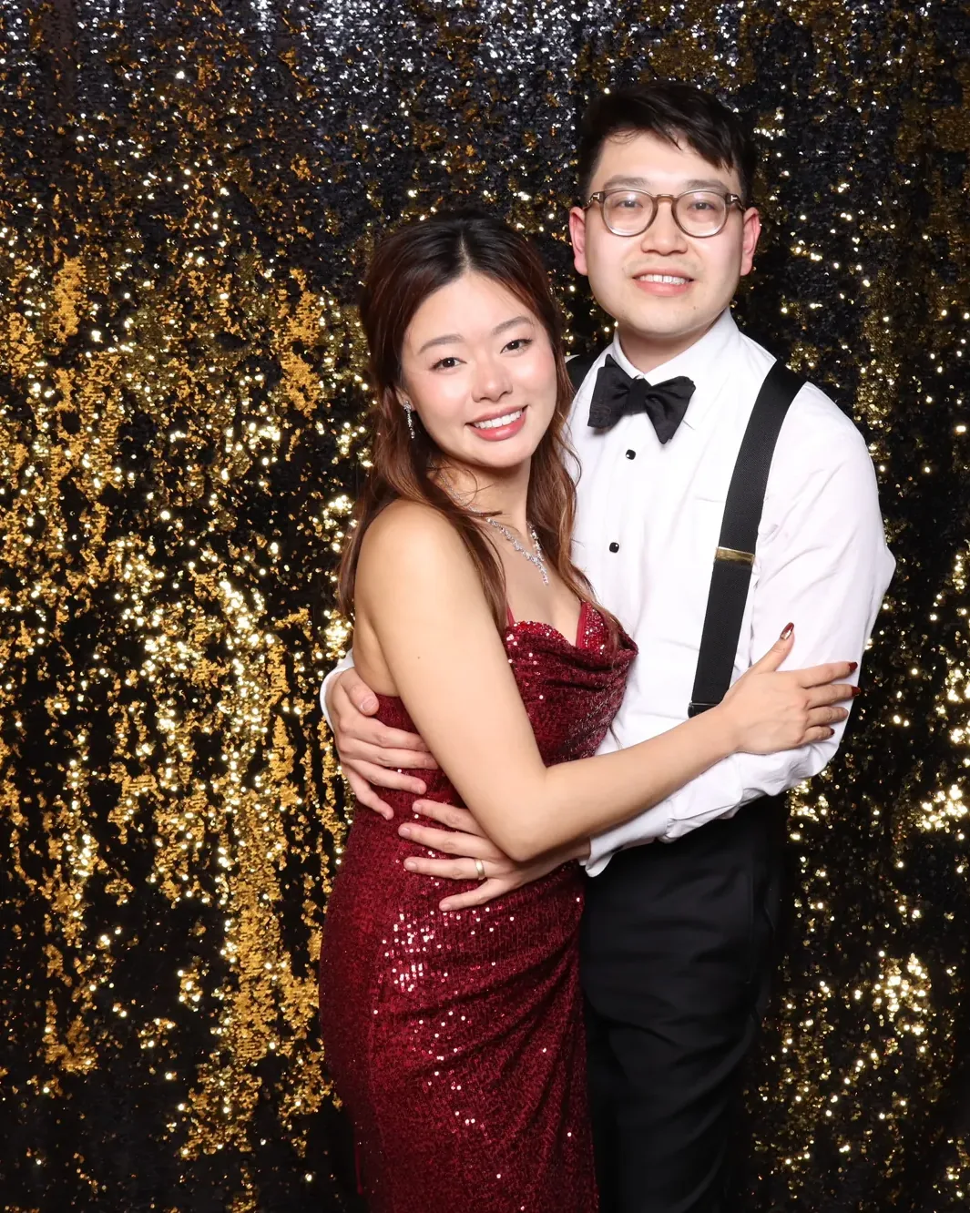 Couple in formal wear against a black and gold sequin photo booth backdrop