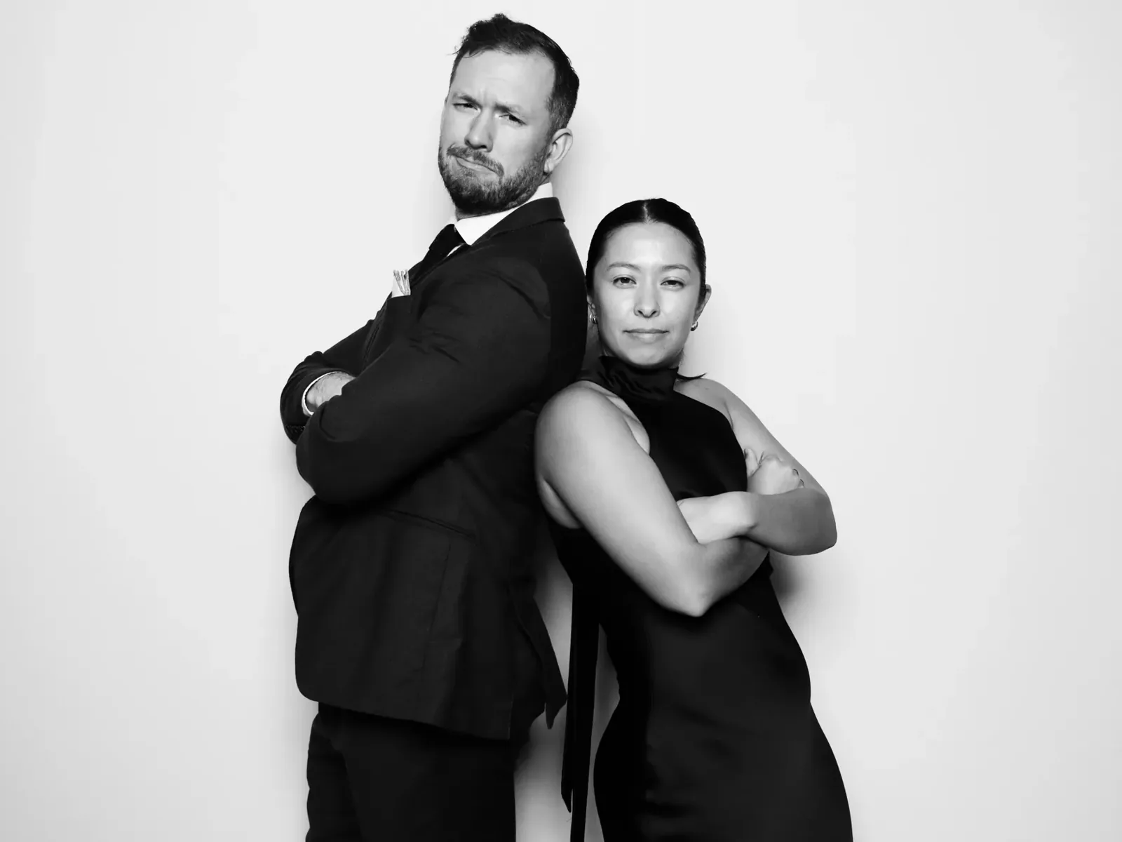 Playful back-to-back pose in a black and white luxury photo booth