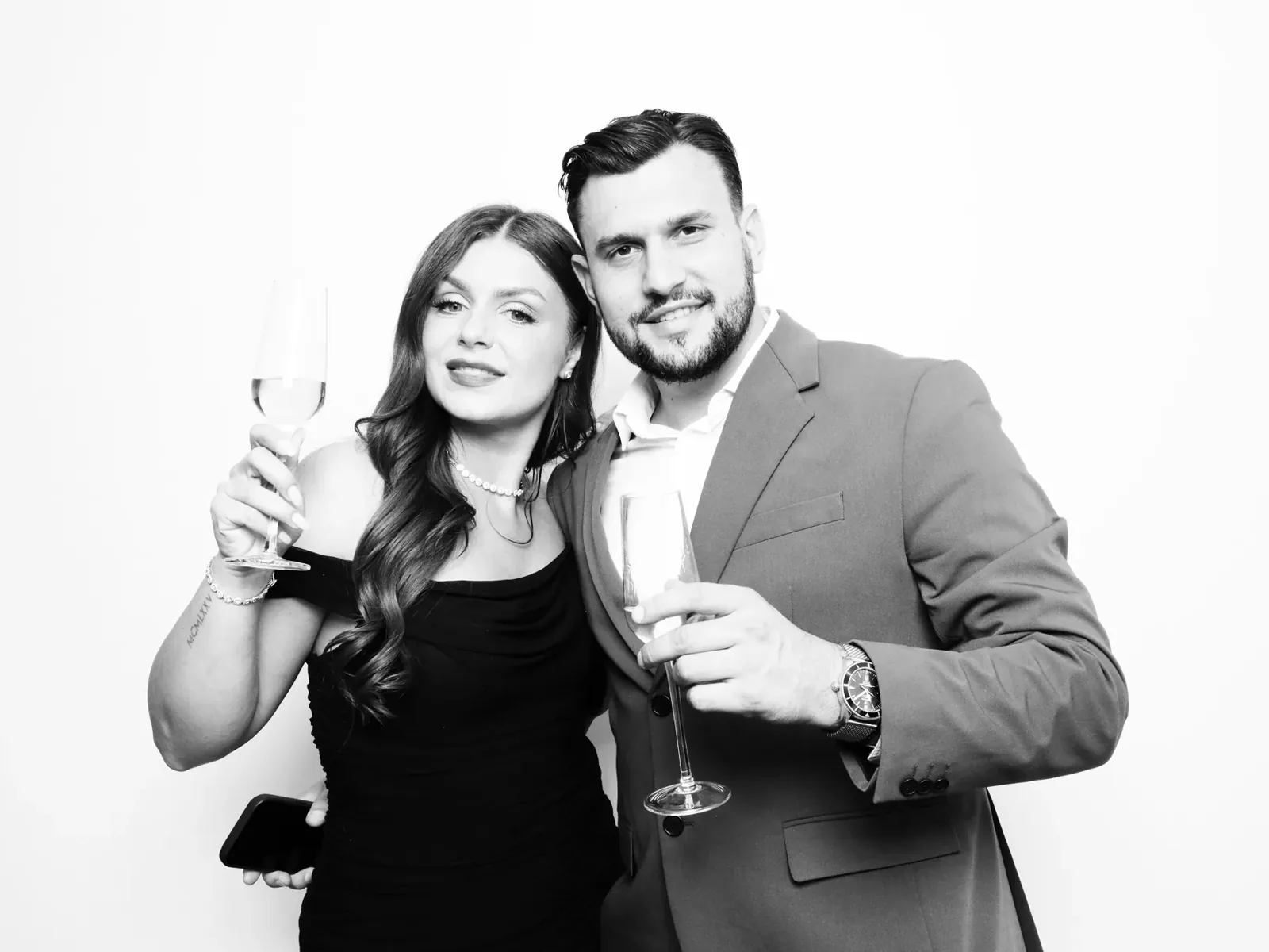 Couple raising champagne in a black and white photo booth rental