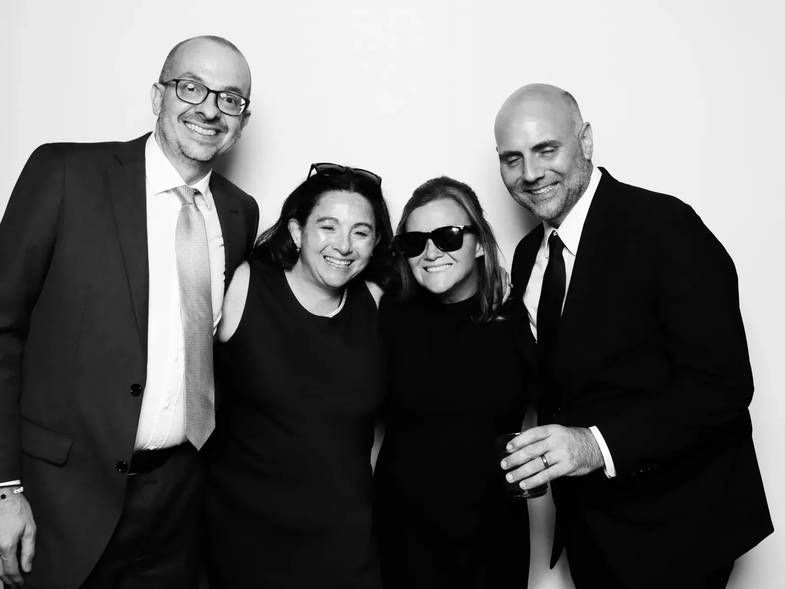 Four wedding guests in formal wear in a black and white glam photo booth