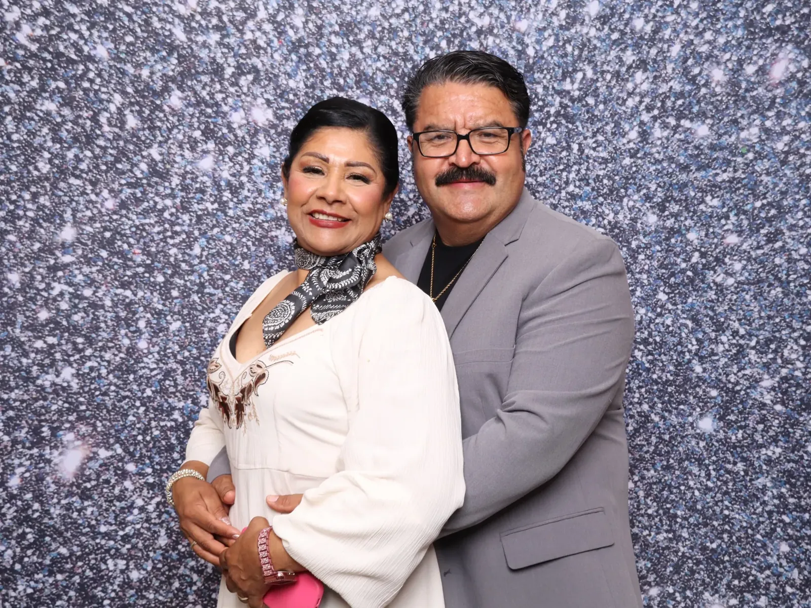Couple celebrating in front of a silver sequin backdrop