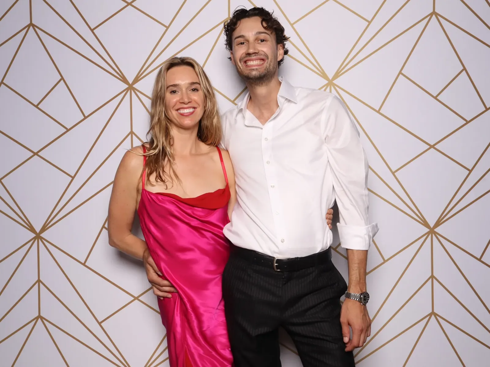Couple in front of a white and gold geometric photo booth backdrop